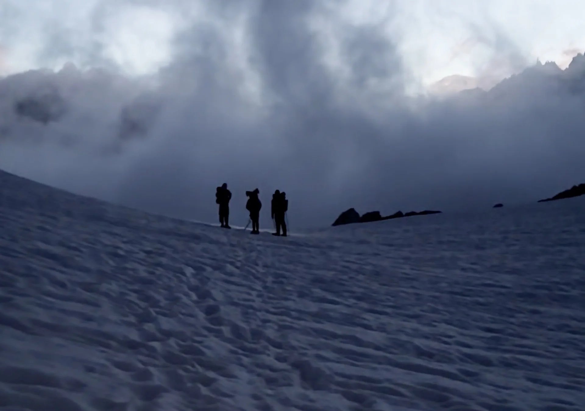 Three hikers in a snowy mountain landscape